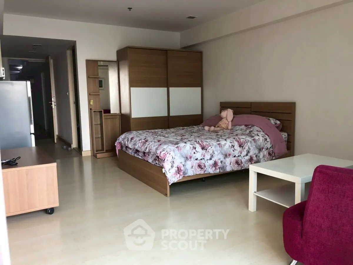 Spacious bedroom with modern furniture and floral bedding in a cozy apartment.