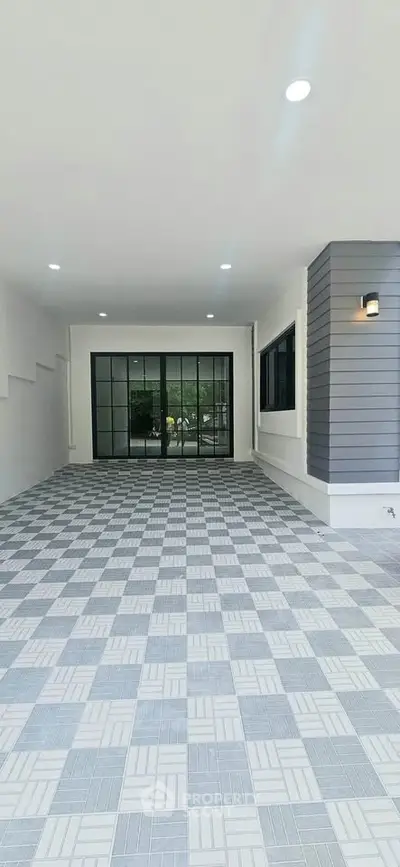 Spacious modern entrance with stylish tiled flooring and large glass doors.