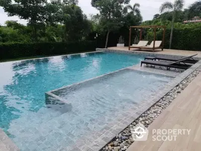 Luxurious outdoor swimming pool with sun loungers and lush greenery