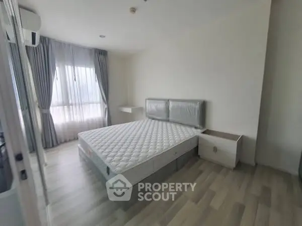 Spacious bedroom with large window and modern furnishings