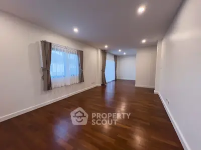 Spacious empty living room with hardwood floors and elegant curtains, perfect for customization.