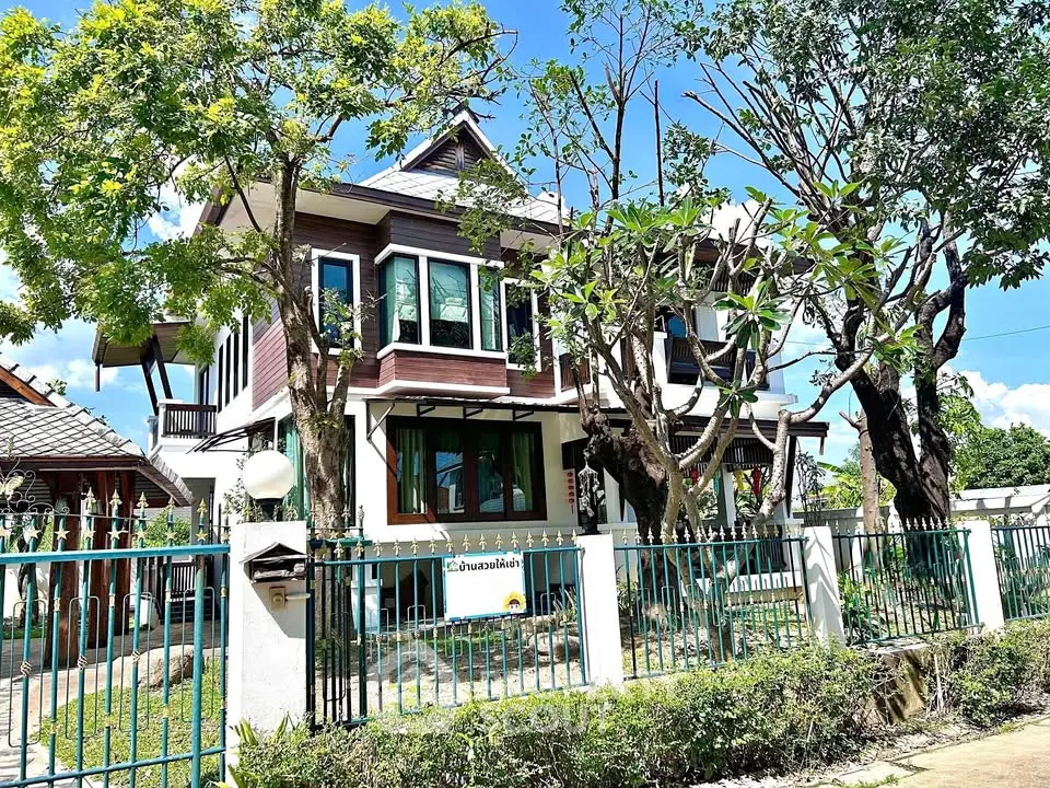 Charming two-story house with lush garden and blue sky backdrop