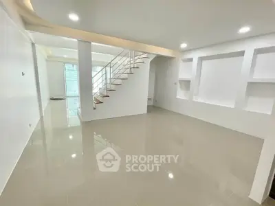 Spacious modern living room with sleek staircase and recessed lighting