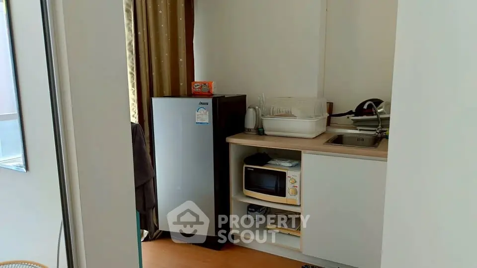 Compact kitchen with fridge, microwave, and sink in modern apartment.