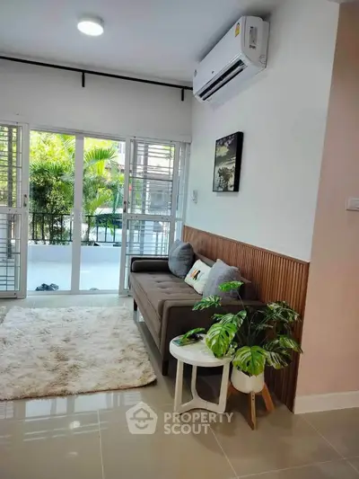 Charming living room with cozy sofa, lush garden view, and modern air conditioning.