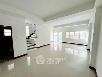 Spacious open-plan living room with large windows and modern staircase