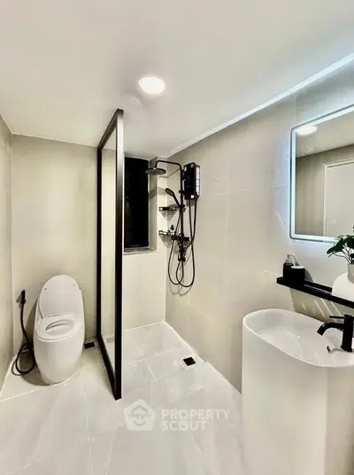 Modern bathroom with sleek fixtures and minimalist design, featuring a glass shower partition and elegant lighting.