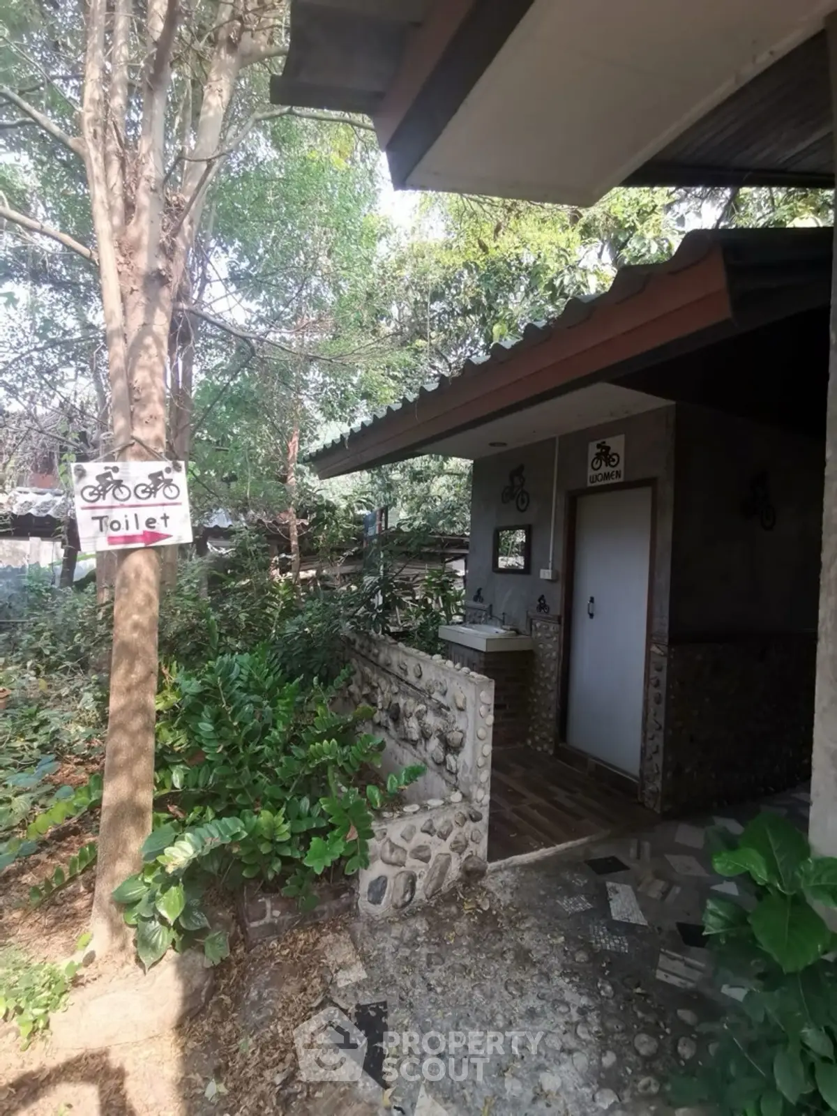 Charming rustic outdoor toilet with stone accents and lush greenery
