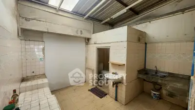 Spacious rustic kitchen with tiled walls and open layout, featuring a sink and countertop.