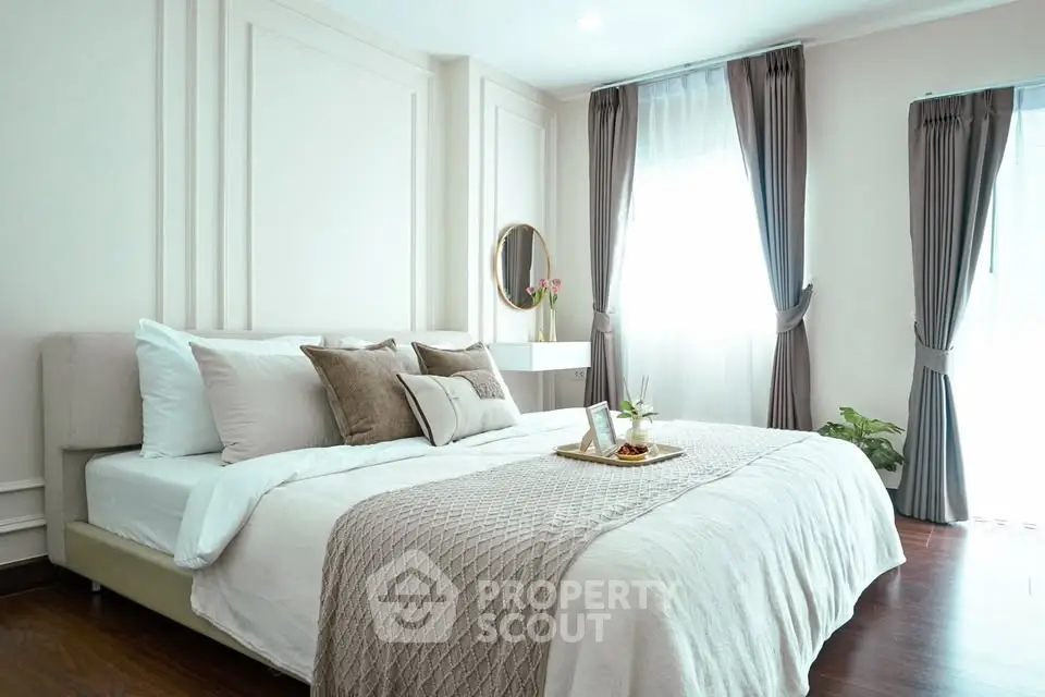 Elegant bedroom with cozy bedding and natural light, perfect for relaxation and comfort.
