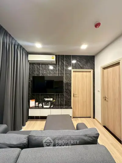 Modern living room with sleek black accent wall, stylish gray sofa, and mounted TV for a contemporary feel.