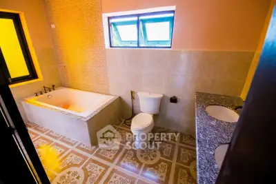 Spacious bathroom with bathtub and dual sinks, featuring elegant tile flooring and modern fixtures.