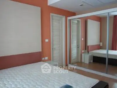 Spacious bedroom with mirrored closet and modern design.
