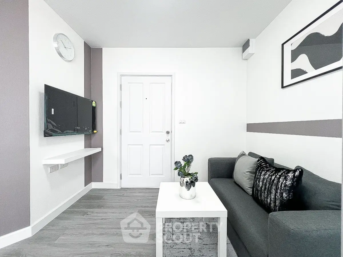 Modern living room with sleek decor and wall-mounted TV, featuring a stylish gray sofa and minimalist design.