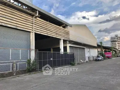 Spacious industrial warehouse exterior with ample parking and secure fencing, ideal for business operations.