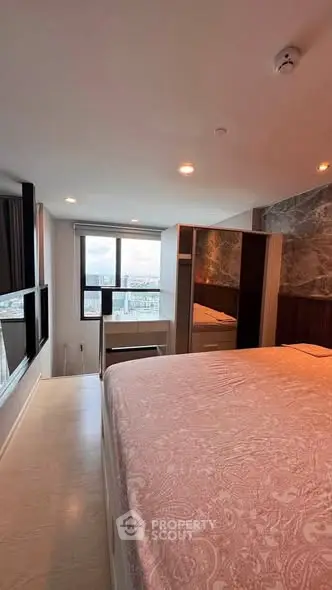 Spacious bedroom with large windows offering a stunning city view, modern decor, and ample natural light.