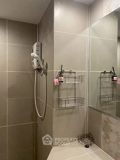 Modern bathroom with sleek tiles and wall-mounted shower in contemporary apartment.