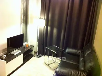 Cozy living room with modern black leather sofa and sleek TV stand, perfect for relaxation.