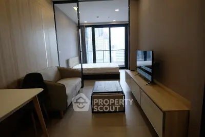 Modern studio apartment with city view, featuring cozy living area and sleek furnishings.