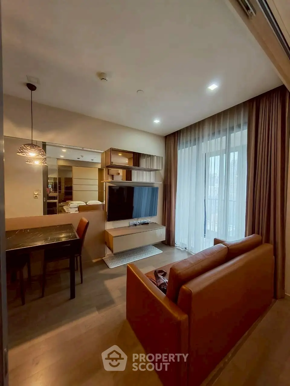 Modern living room with stylish furniture and large TV, featuring floor-to-ceiling windows and elegant lighting.
