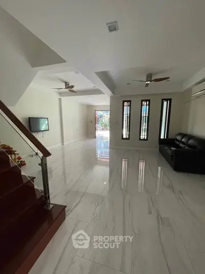 Spacious modern living room with sleek marble flooring and stylish ceiling fans.