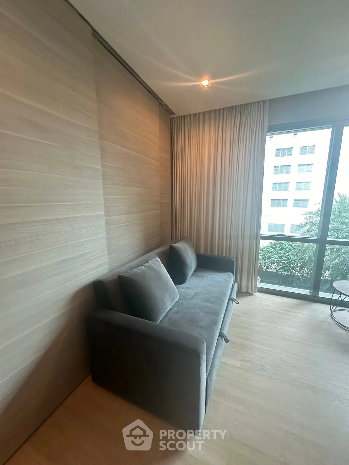 Cozy living room with modern sofa and large window offering natural light and city view.