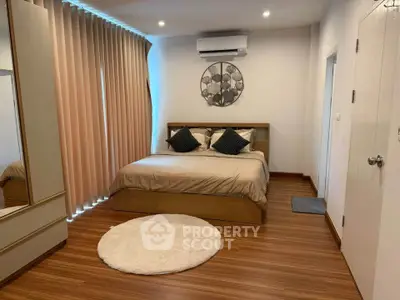 Spacious bedroom with modern decor and wooden flooring, featuring a cozy bed and stylish wall art.