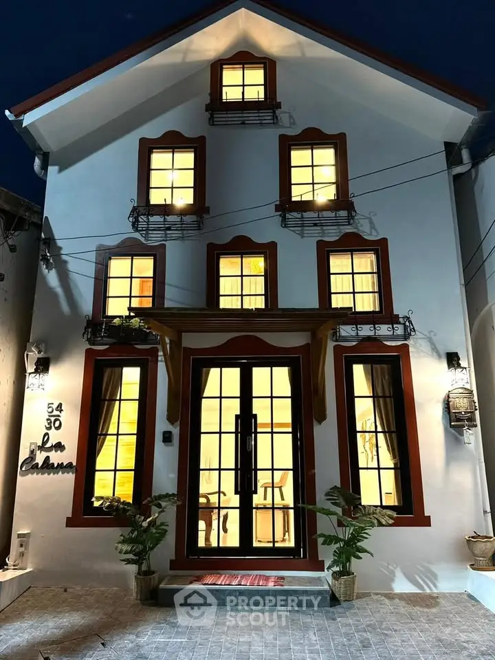 Charming three-story house with illuminated windows and elegant facade, perfect for cozy living.