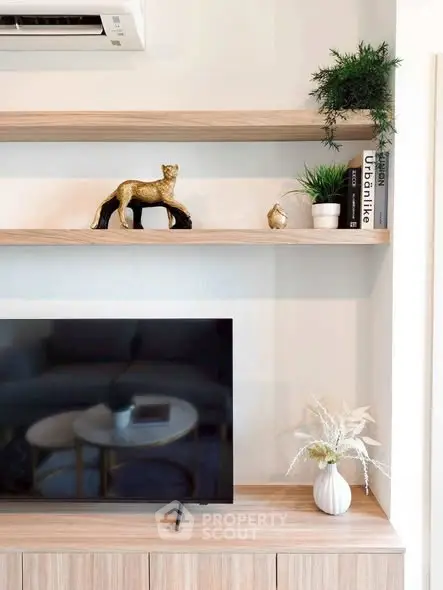 Modern living room with stylish decor and flat-screen TV on wooden cabinet.