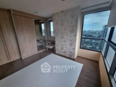 Spacious bedroom with floral accent wall and city view window