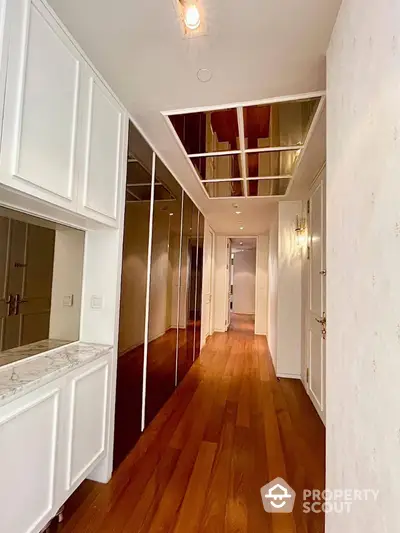 Elegant hallway with wooden flooring and mirrored closets in modern apartment