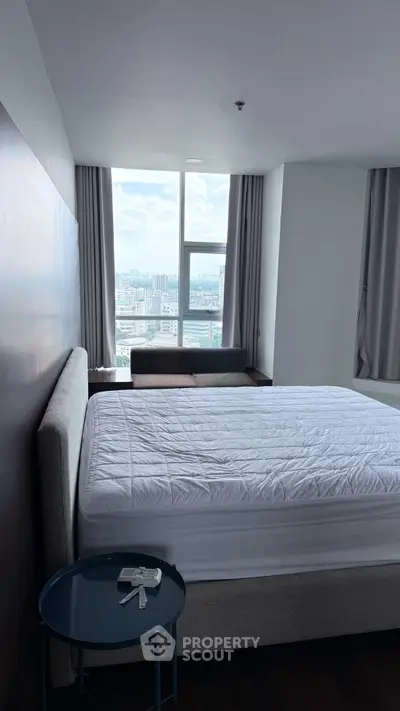 Modern bedroom with large window offering stunning city view, featuring a cozy bed and stylish decor.