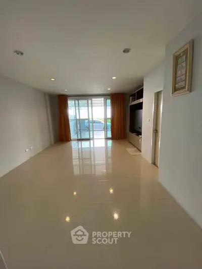 Spacious living room with large windows and balcony access, perfect for natural light and modern living.