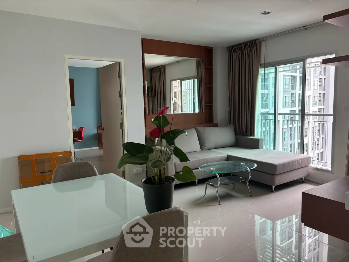 Modern living room with sleek furniture and large windows offering city views.