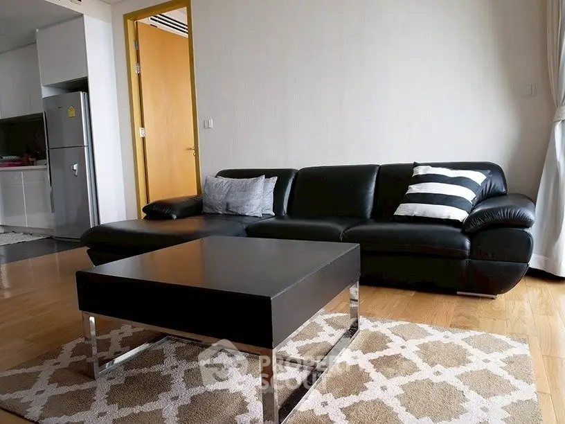 Modern living room with sleek black leather sofa and stylish coffee table.