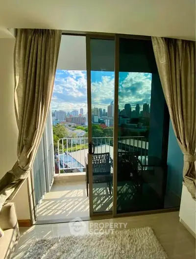 Stunning city view from a modern apartment balcony with elegant curtains and cozy seating area.