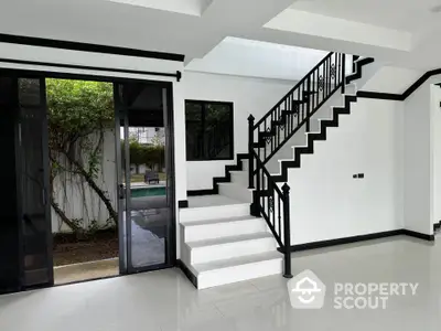 Modern interior with sleek staircase and garden view through glass doors