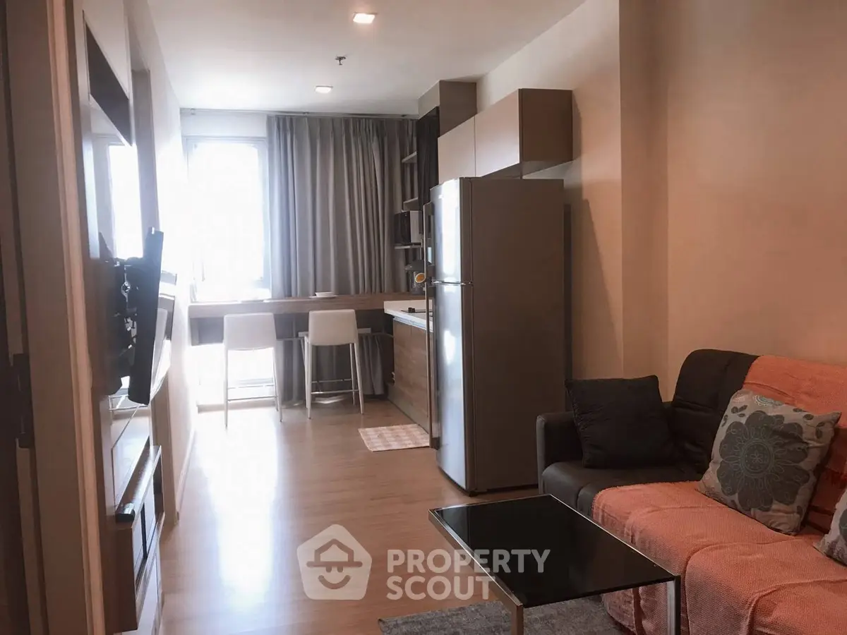 Modern open-plan living room with kitchen and dining area, featuring sleek furniture and natural light.