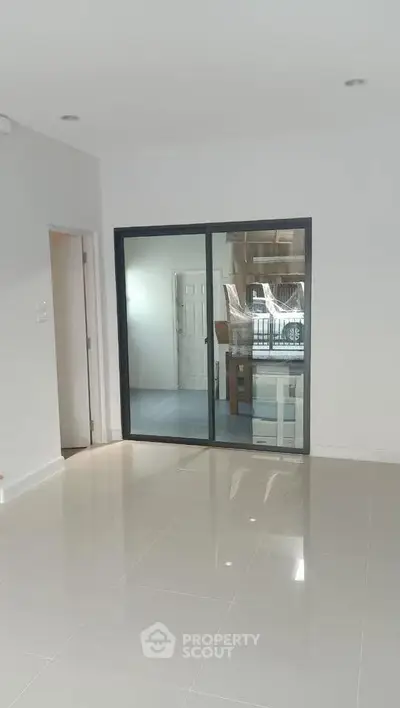 Spacious modern interior with sleek tiled flooring and glass sliding doors.