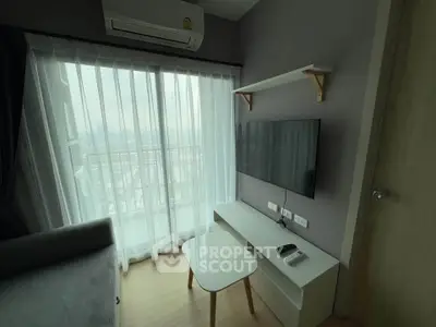 Modern living room with large window and wall-mounted TV in a cozy apartment.