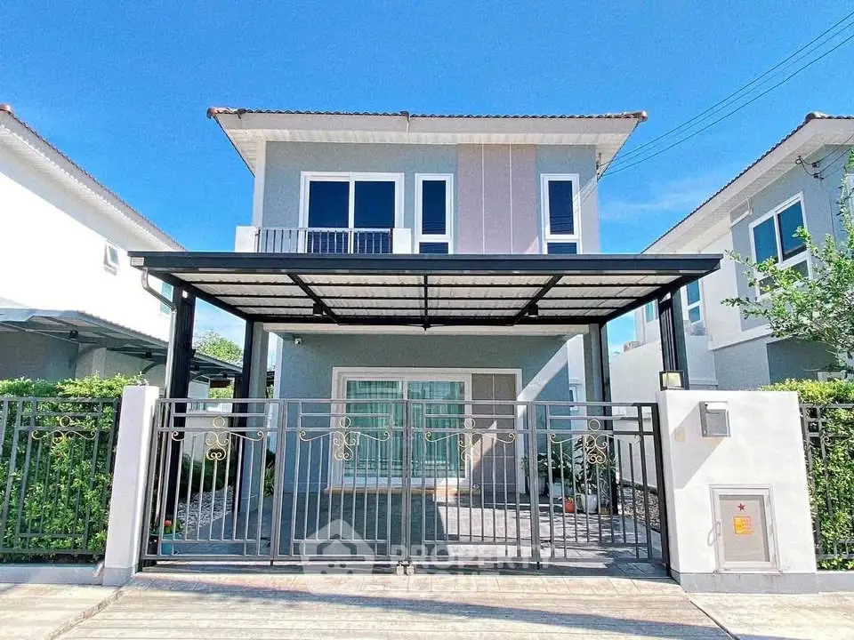 Modern two-story house with gated driveway and sleek design in a suburban neighborhood.