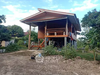 Charming elevated wooden house with lush greenery and rustic appeal, perfect for serene countryside living.