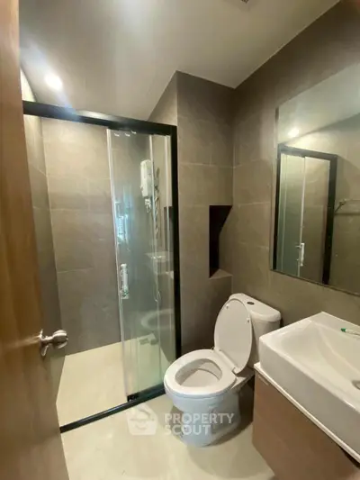 Modern bathroom with glass shower and sleek fixtures in contemporary apartment.