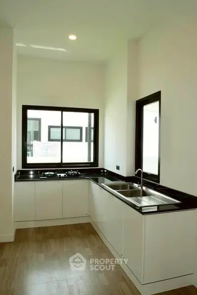 Modern kitchen with sleek black countertops and large windows for natural light.