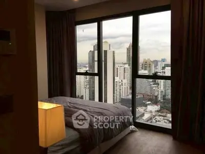Luxurious bedroom with stunning city view from floor-to-ceiling windows in a high-rise apartment.