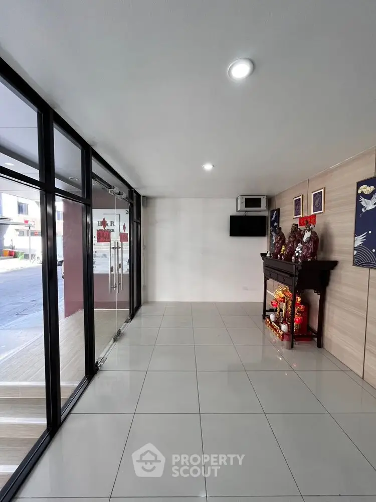 Spacious entrance with tiled flooring and glass doors in modern building.