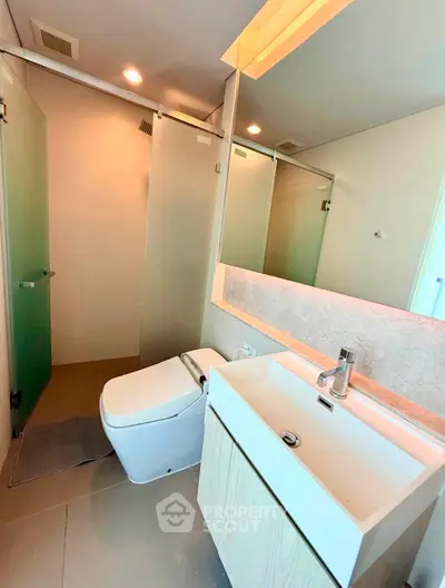 Modern bathroom with sleek fixtures and glass shower door in contemporary apartment.