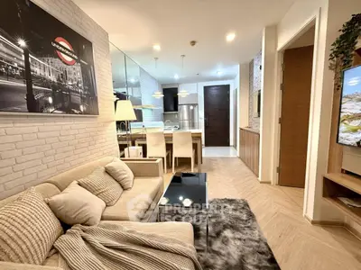 Stylish modern living room with cozy sofa, chic decor, and open kitchen layout in a contemporary apartment.