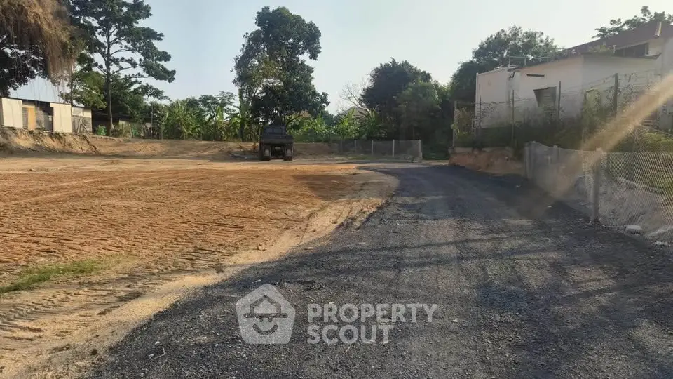 Spacious land plot with potential for development, surrounded by greenery and clear skies.