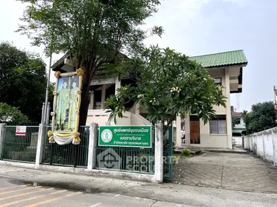 Charming two-story building with green roof and lush garden, ideal for serene living or office space.